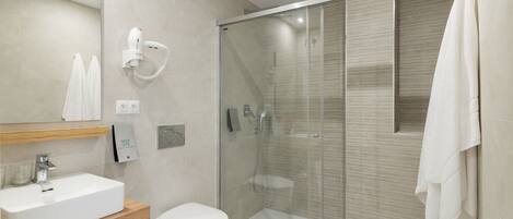 A modern bathroom with a glass-enclosed shower, a white sink, and a toilet.