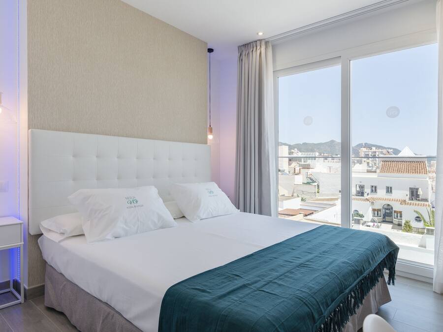 A modern hotel room with a large bed, a view of the city, and a balcony.