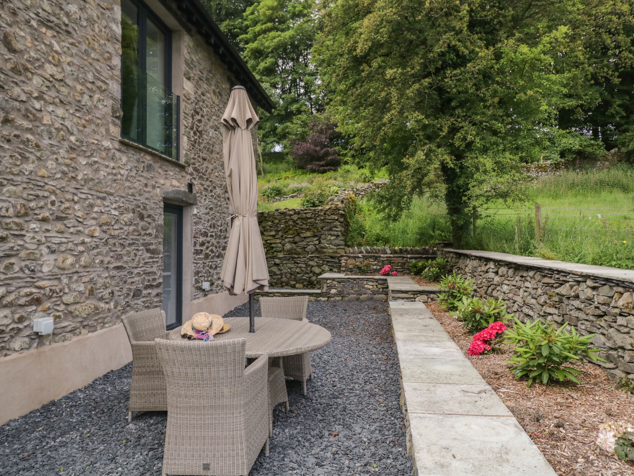 An outdoor patio with wicker furniture and a stone wall.