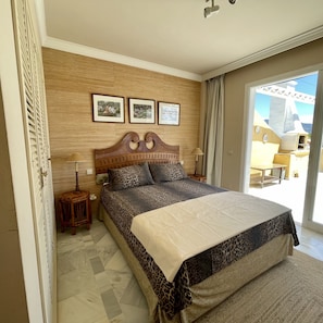 A bedroom with a large bed, wooden headboard, and three framed pictures on the wall.