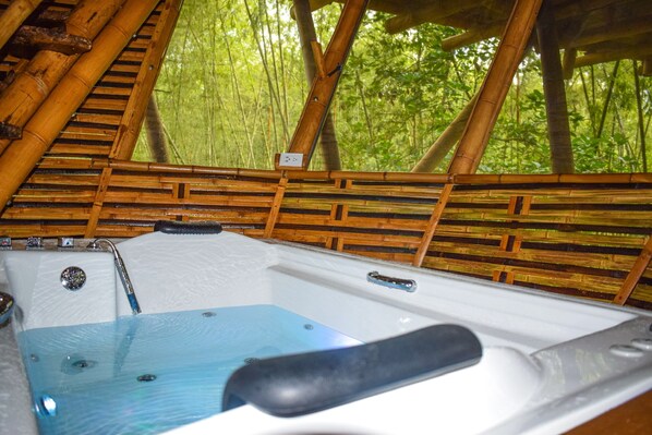 A hot tub with a bamboo structure and a view of a forest. - Eco Hotel Hacienda El Diamante (Guadalajara de Buga)