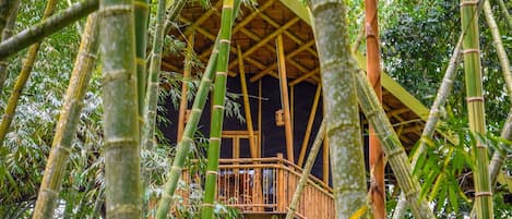 A bamboo structure with a wooden balcony and a thatched roof.