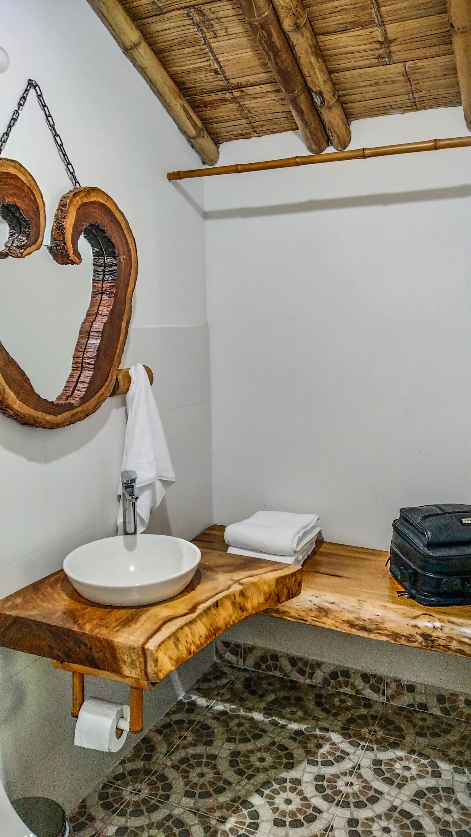 A bathroom with a wooden vanity, a large mirror, a sink, and a shower area.