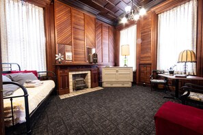 Ein Zimmer mit einem Bett, einem Schminktisch, einem Tisch mit Stühlen, einer Lampe und einem Kamin.