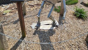 A metal sculpture of a human figure in a park setting.