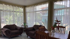 Un salon avec deux canapés marron, une table à manger en bois et des chaises. Une petite table avec un pot de plante est placée au centre.