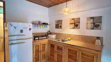 A kitchen with wooden cabinets, a white refrigerator, and a hanging light fixture.
