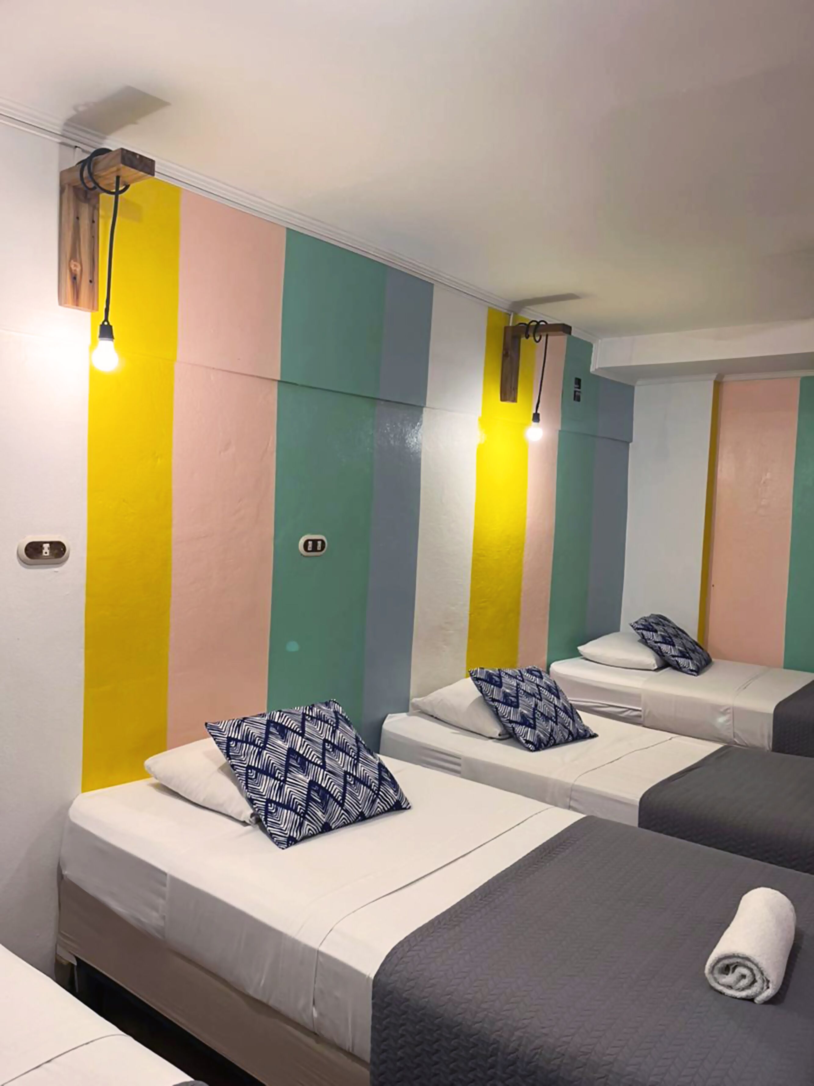 Une chambre d’hôtel avec deux lits, chacun agrémenté d’un oreiller à motifs et d’une serviette roulée.