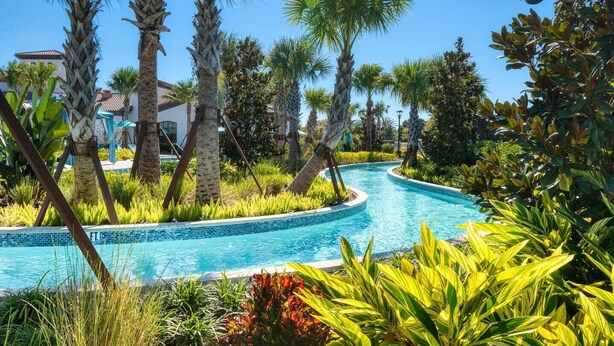 Una piscina envoltada de palmeres i plantes tropicals.