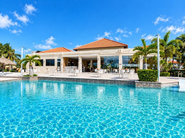 A resort with a swimming pool, outdoor seating, and a bar area.