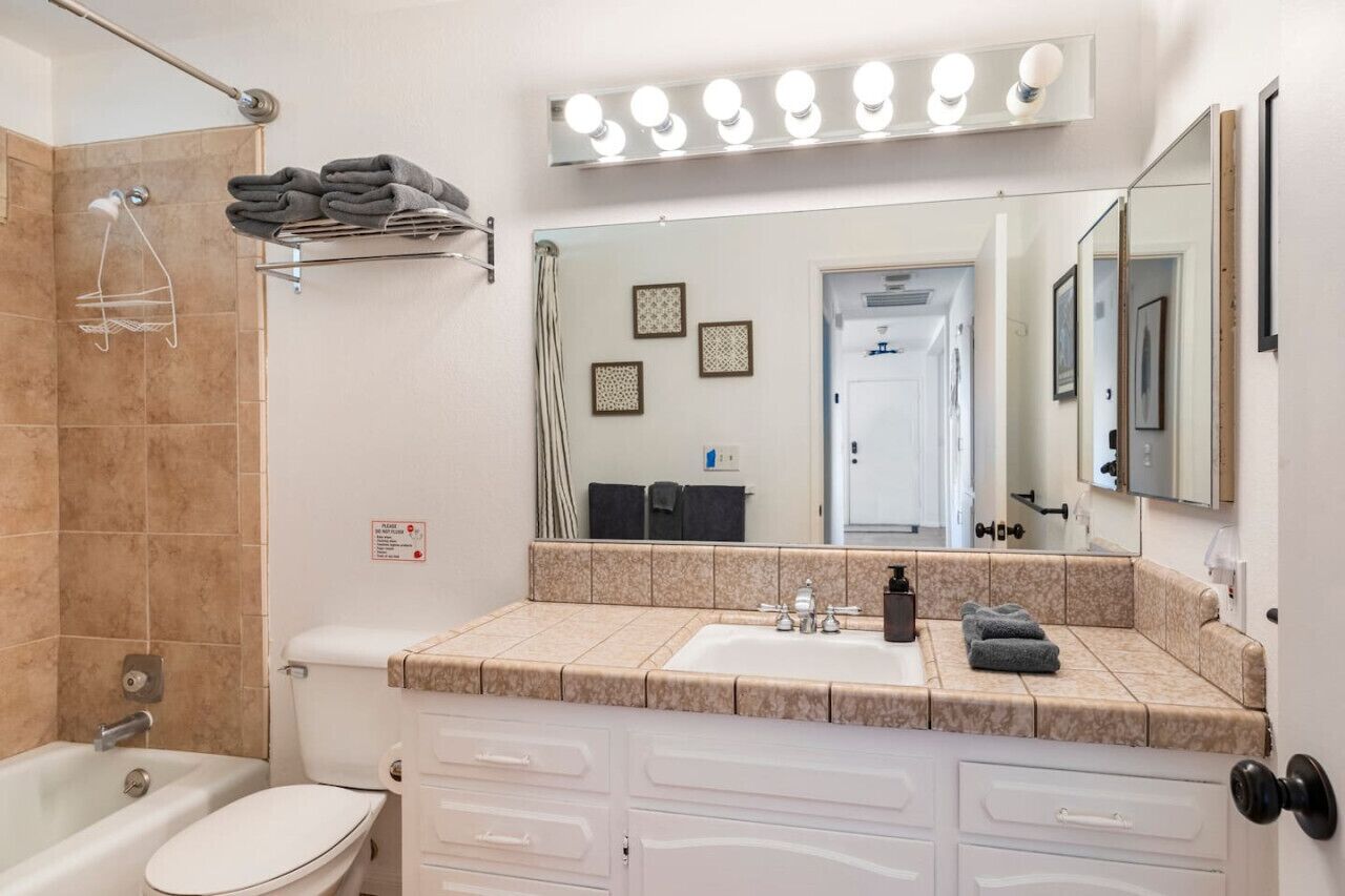 Un baño con lavamanos, espejo, toallero y ducha.