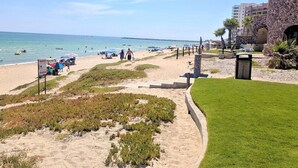 Ein Strand mit einem Pfad, der zu einem Gebäude mit einer Steinverkleidung führt.