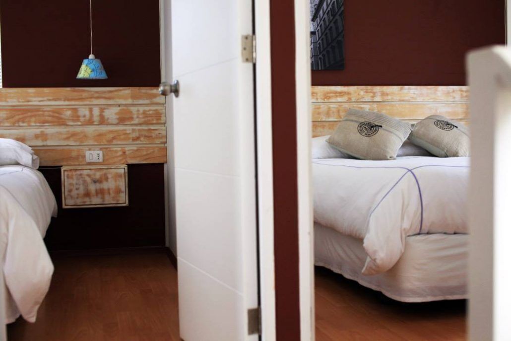 A hotel room with a wooden headboard, a bed with white bedding, and a hanging light fixture.