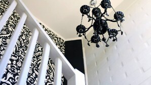 Uma escadaria com corrimão em padrão preto e branco e um lustre preto.