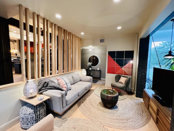 A modern living room with a grey sectional sofa, a round coffee table, and a TV on a wooden stand. - Champa House - Easy access to Rino/Ballpark/Downtown (Denver)
