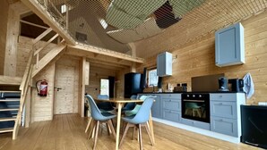 Une cuisine moderne avec un plancher en bois, un coin repas avec des chaises bleues et un escalier.