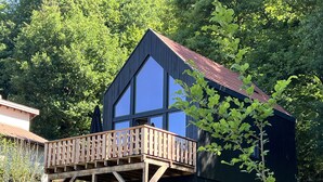 Une maison moderne dotée d’une terrasse en bois et de grandes fenêtres.