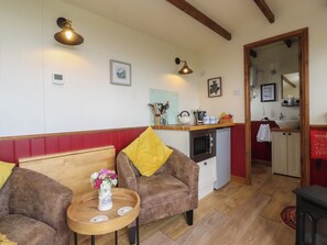 Una stanza accogliente con angolo cottura, zona pranzo con due divani e pavimento in legno.