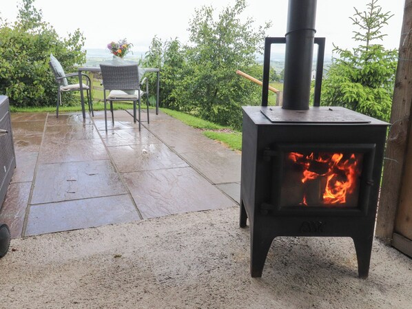 A wood-burning stove, outdoor seating with chairs, and a view of the landscape. - The Journeyman Luxury Shepherds Hut (Barnoldswick)