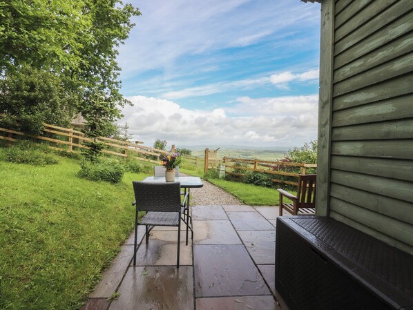 Une terrasse avec une table et des chaises, une clôture en bois et une vue sur la campagne.