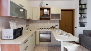 Una cocina compacta equipada con microondas, estufa, horno y un pequeño comedor.