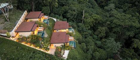 Un conjunto de casas modernas con tejados rojos ubicadas en un bosque denso, rodeadas de abundante vegetación.
