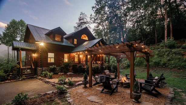 A log cabin with a covered patio, outdoor seating, and a fire pit. - Pet-Friendly Blue Ridge Cabin on 9 Acres! Views, Theater, Game Room, Trails! (Blue Ridge)