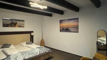 A bedroom with a bed, a chair, and two wall-mounted paintings.