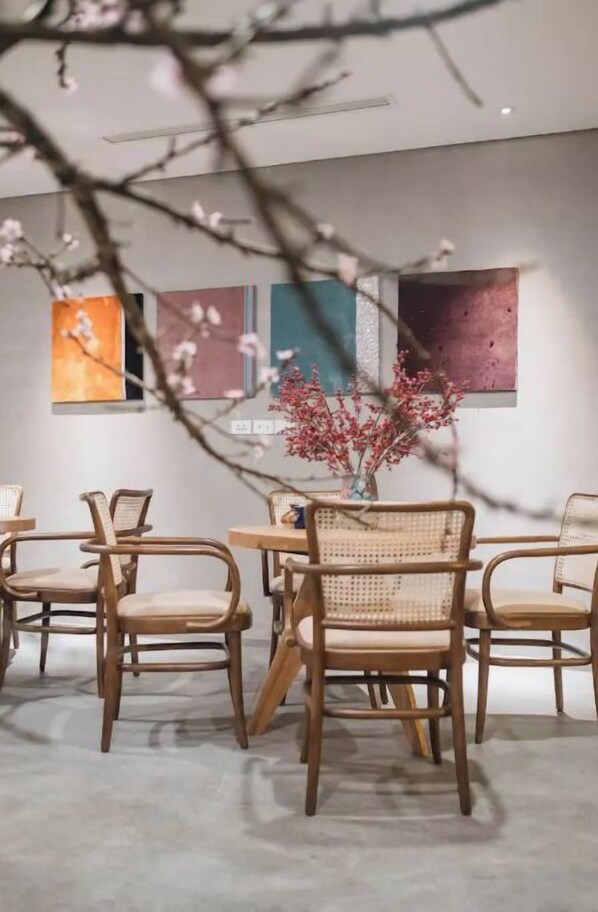 A room with a round table and six wicker chairs, a vase with red flowers, and three abstract paintings on the wall. - ★ Satori ★ Luxury Duplex 2BR w Tub ★ Hoan Kiem ★ (Hà Nội)