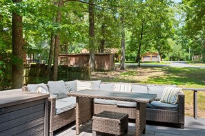 Une terrasse extérieure avec des meubles en osier et une plateforme en bois.