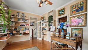 A room with wooden flooring, a staircase, a dining area with a table and chairs, and shelves with various items. - LUXURY SUITE KING AT OLD COLORADO INN (Stuart)