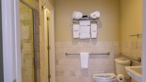Un baño con cabina de ducha de vidrio, inodoro y lavamanos.