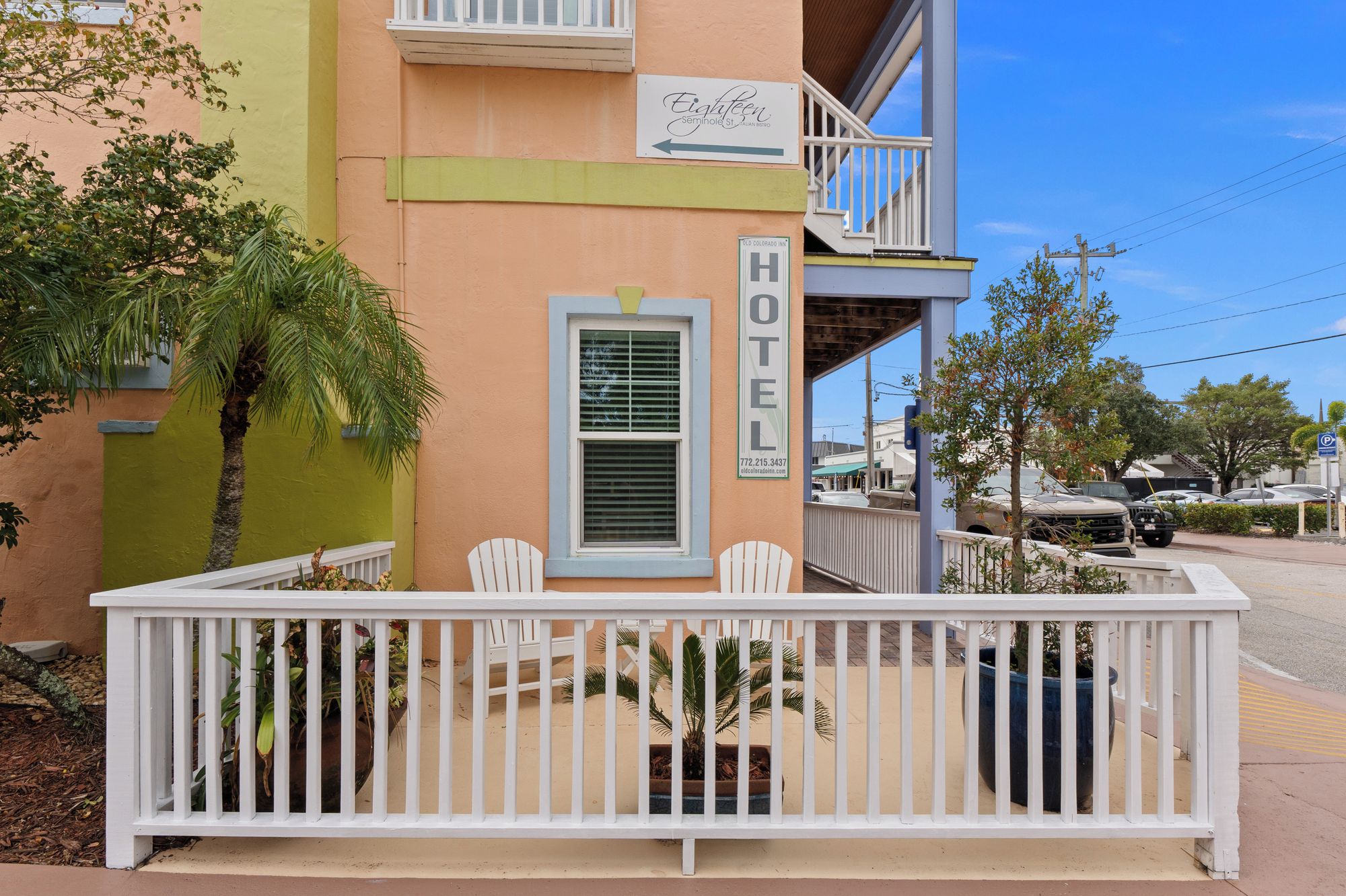 A hotel with a balcony, a sign indicating it's a hotel, and a window with blinds.