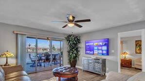 A living room with a sofa, a coffee table, a TV, and a ceiling fan. - Lakefront Family, 3 Bedroom, 2 Bath, Private Patio, Heated Pool, Jacuzzi  (Phoenix)