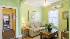A living room with a beige sofa, a wooden coffee table, a floor lamp, and a potted plant. - THE BERMUDA SUITE  AT OLD COLORADO INN (Stuart)
