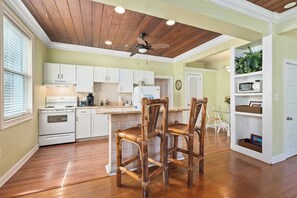 A kitchen with white cabinets, a wooden ceiling, and a dining area with a table and chairs. - THE KEY WEST SUITE AT OLD COLORADO INN (Stuart)
