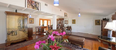 Amplia sala de estar con un mueble de madera grande, un sofá, una mesa de centro y un comedor con sillas y una mesa.
