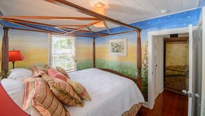A bedroom with a four-poster bed, a nightstand, a red lamp, and a window with blinds. - THE SERENITY SUITE AT OLD COLORADO INN (Stuart)