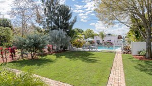 A well-maintained garden with a swimming pool, a brick pathway, and various plants and trees. - THE SERENITY SUITE AT OLD COLORADO INN (Stuart)