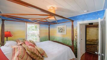 A bedroom with a four-poster bed, a nightstand, a lamp, a window with blinds, and a door leading to another room.