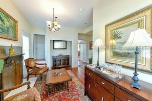 A spacious living room with a fireplace, a chandelier, and a large framed painting. - EVINRUDE SUITE AT OLD COLORADO INN (Stuart)