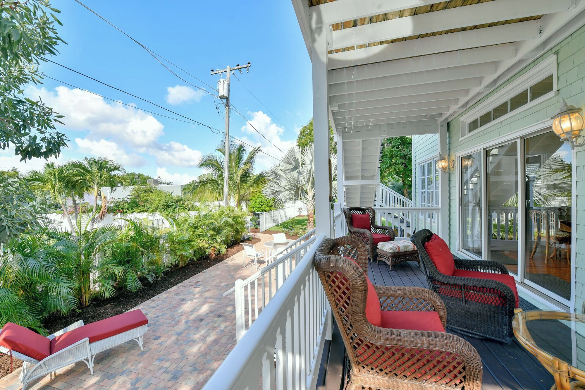 A covered outdoor area with wicker furniture and a white railing.