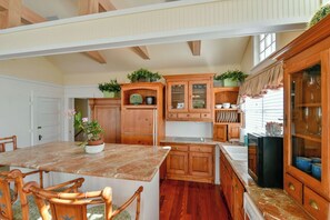 A spacious kitchen with wooden cabinets, a marble countertop, and a dining area with chairs. - LANGFORD SUITE AT OLD COLORADO INN (Stuart)