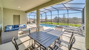 A covered patio area with a pool, outdoor furniture, and a view of the landscape. - 7655 Oakmoss Loop (Davenport)