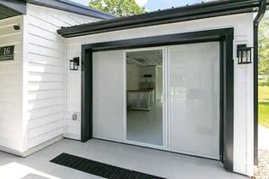 Ein modernes Gebäude mit einem großen Glastür-Eingang, einem sichtbaren Innenraum mit Heizkörper und einem Schild mit der Nummer 16 an der Wand.