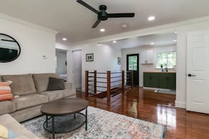 Relax in this inviting living space with a sofa, coffee table, and staircase leading to a kitchen area.