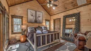 A wooden cabin bedroom with a bed, a large mirror, and a ceiling fan. - Luxury Cabin-Chic getaway w/hot tub, Gated community, River access, Easy drive (Blue Ridge)