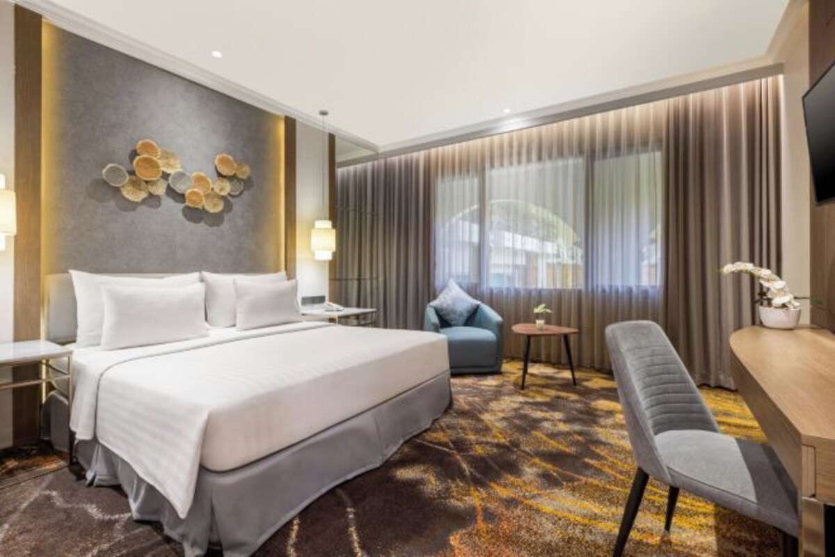 Une chambre d’hôtel avec un grand lit, un bureau, une chaise et un téléviseur.