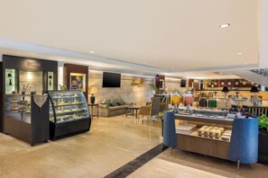 Un vestíbulo de hotel con una vitrina de joyería, zona de estar y un bufé.