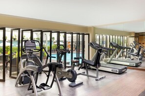 Un gimnasio con cintas de correr, elípticas y un espejo grande.